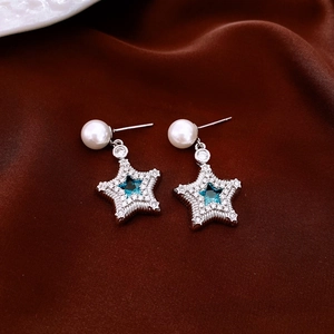 Macro view of star pendant earring with a blue gemstone and pavé diamonds on velvet