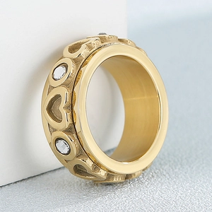 Golden wide heart ring with inlaid sparkling zircon stones on a white background