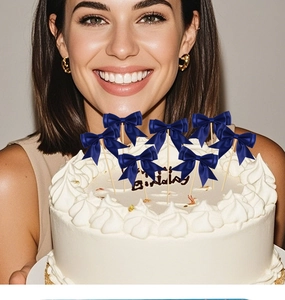 Detail of dark blue ribbon bow cake toppers on white cream cake for birthday party