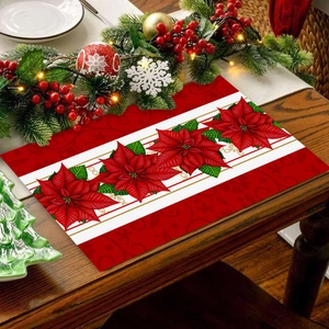 Christmas placemat with red poinsettia flowers and green leaves on wooden table setting