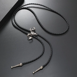 Detail of vintage silver ram skull bolo tie with black braided cord and metallic tips