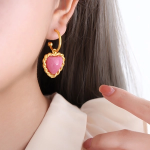 Vintage gold hoop earrings with pink heart charms and pearl accents shown on a model