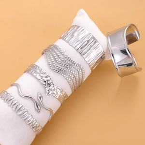 Set of five silver open bangles featuring textured, wavy, and polished stainless steel designs