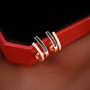 Detail of gold-plated double-row geometric earrings with black enamel and zircon accents