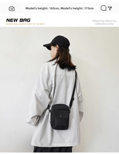 Detail of black canvas crossbody bag showing front flap pocket and adjustable strap