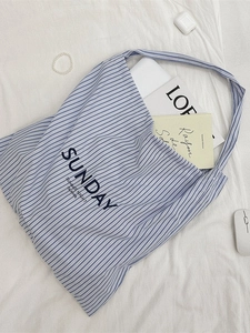 Blue and white striped canvas tote bag with SUNDAY print shown with a laptop on white sheets
