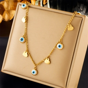 Layered gold titanium steel necklace with evil eye and heart pendants on a display pillow