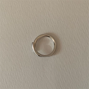 Close-up of a silver smile engraved ring on a textured cream leather background