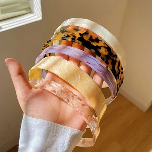 Close-up of assorted tortoiseshell and marble acetate wide headbands held in hand