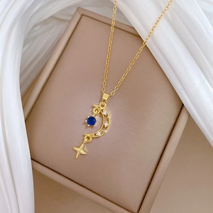 Detailed macro view of gold star and moon pendant with blue gemstone in a gift box