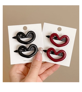 Detail of four heart-shaped hair clips in black and wine red colors on a card