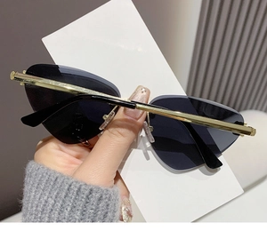 Detail of rimless triangle cat-eye sunglasses with gold metal panther head temples