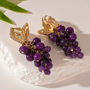 Gros plan de boucles d'oreilles grappe de raisin violettes avec feuilles dorées et cristaux