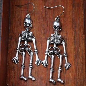 Macro shot of silver gothic skeleton dangle earrings on a rustic wood base for Halloween