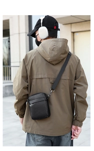 Outdoor street style view of a black PU leather crossbody bag worn by a model