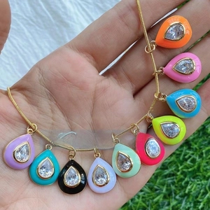 Macro shot of colorful enamel teardrop pendants with inlaid zircons on a gold chain