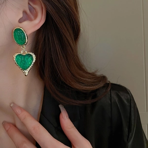 Vintage green resin heart drop earrings with gold hammered frames on a model