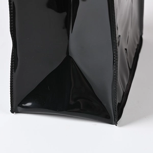 Minimalist black PVC gift bag with glossy patent finish and round handles in a sleek design