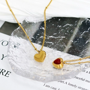 French vintage style gold heart necklaces with red agate on a decorative glass tray