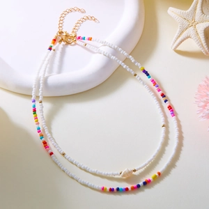 Détail d'un collier de perles colorées avec pendentif coquillage doré sur plateau