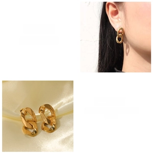 Close-up of polished 18K gold titanium steel geometric chain link earrings on satin