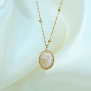 Close-up of 14K gold plated necklace with faceted white natural stone on white silk