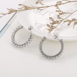 Close-up of silver C-shape earrings featuring square-cut white zircons on a white plate