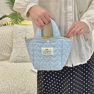 Detail of light blue quilted handbag with heart pattern stitching and woven Happy label