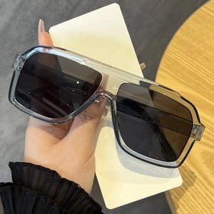 Detail view of transparent grey square sunglasses with dark lenses on wooden background