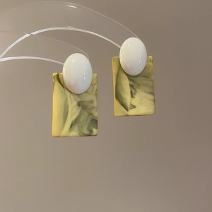 Detailed view of colorful floral earrings with green marble texture hanging on a stand