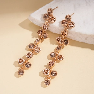 Détail de boucles d'oreilles fleur rose avec strass champagne et pompons élégants