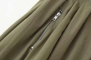 Gros plan sur la fermeture éclair métallique et le tissu plissé vert armée du pantalon
