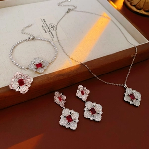 Close-up of a floral silver jewelry set with red gemstones and zircons in a wooden tray