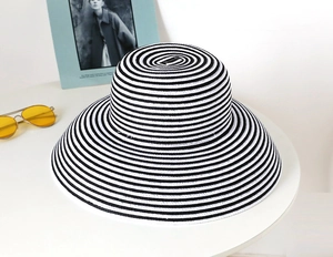 Close-up of black and white striped straw sun hat on table with vintage sunglasses