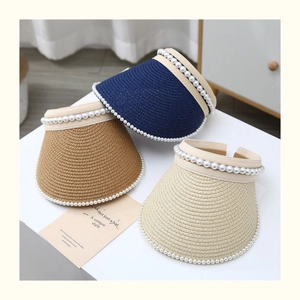 Detailed straw weave of three pearl sun visors in navy, tan, and cream white colors