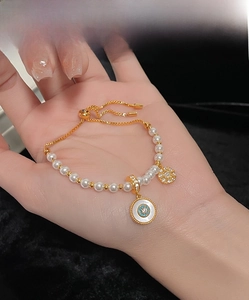 Détail du bracelet en perles dorées réglable avec pendentifs œil et étoile étincelante