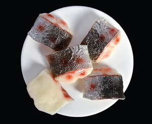Vue macro de cinq modèles réalistes de viande de poisson artificielle sur une assiette blanche