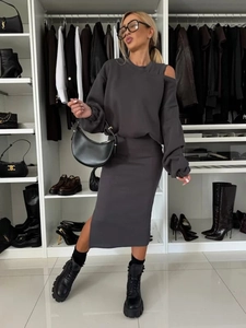 Detail of dark grey knitted set featuring an off-shoulder top and side slit midi skirt