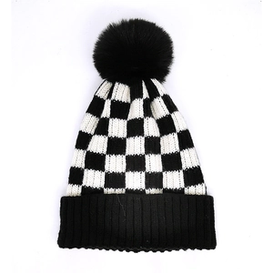 Classic black and white checkered knit beanie with a fluffy pom pom and ribbed cuff