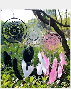 Outdoor view of handmade dream catchers with lace and feathers in black, white and pink
