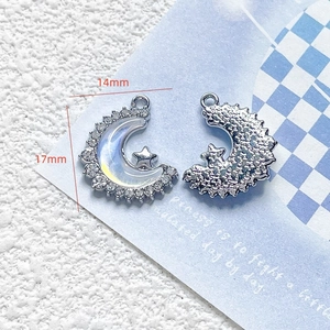 Macro view of silver star and moon charms with iridescent inlay and dimensions
