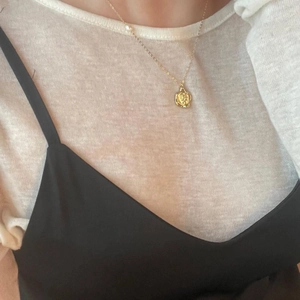 Detail of vintage irregular round gold medal pendant necklace with a small pearl on chain