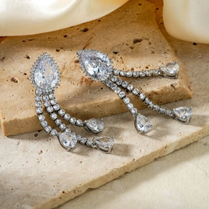 Elegant silver tassel earrings with pear-cut cubic zirconia on luxury silk background