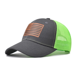 Dettaglio della toppa in pelle con bandiera USA su cappello trucker grigio e verde