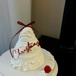 Christmas tree shaped cream cake with a red ribbon bow and red Christmas topper