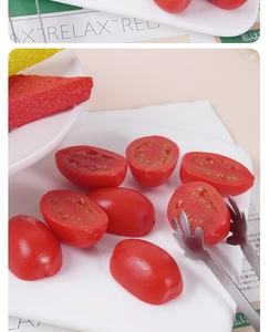 Realistic artificial cherry tomato model with sliced halves and metal food clip on a plate