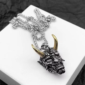 Vintage Hannya mask necklace with golden horns on silver pendant over dark texture