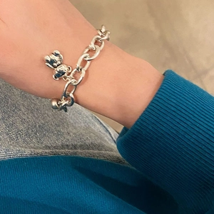 Detailed view of silver teddy bear pendant on minimalist metal chain worn on wrist