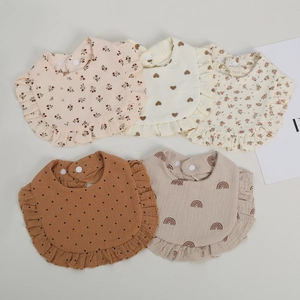 Detail of five-piece muslin cotton baby bibs with ruffle edges and various patterns