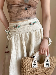 Detail of bohemian acrylic bead woven waist chain on vintage jacquard texture dress
